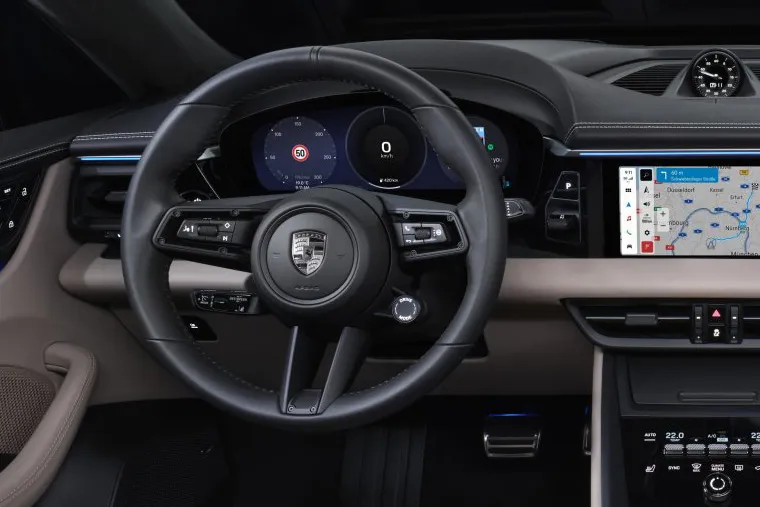 Interior of the electric Porsche Macan showing premium beige leather seats, digital cockpit, and wide infotainment display.