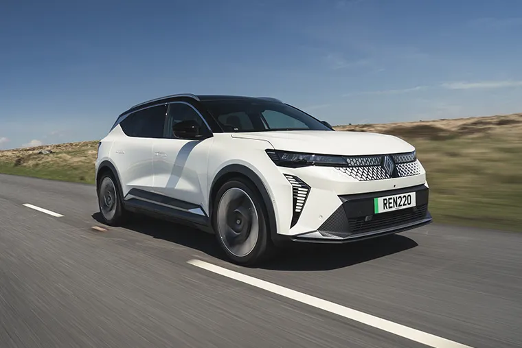 Renault Scenic E-Tech electric SUV driving on open countryside road under clear blue sky.