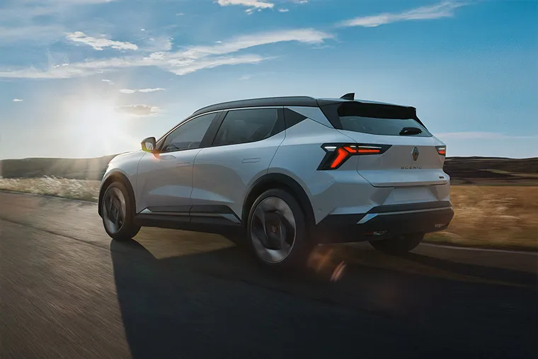 Renault Scenic E-Tech electric SUV driving on a scenic road at sunset – 2024 European Car of the Year.