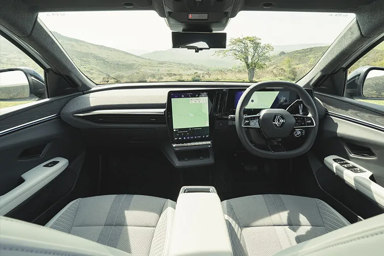 Renault Symbioz interior with twin-screen digital cockpit and panoramic countryside view through windshield.