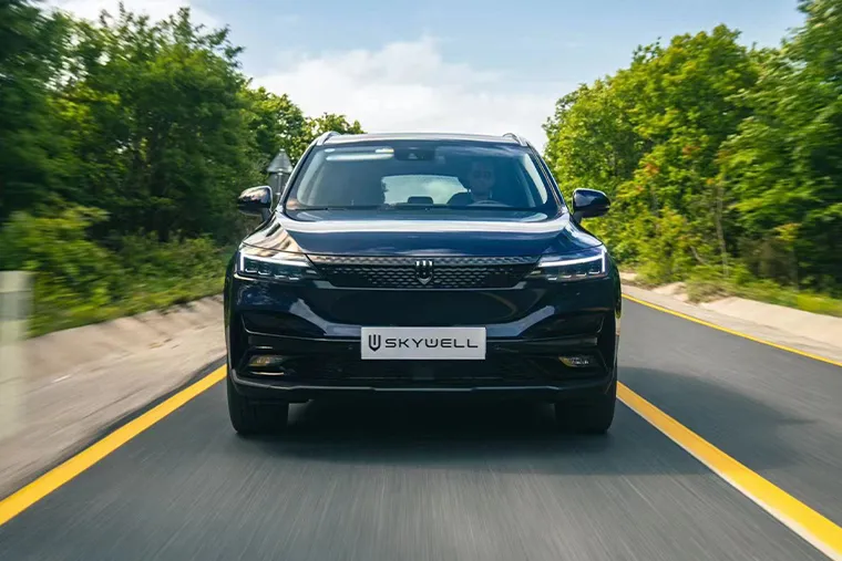 Front view of a black Skywell ET5 electric SUV driving along a tree-lined road, showcasing its sleek LED headlights and modern grille design.