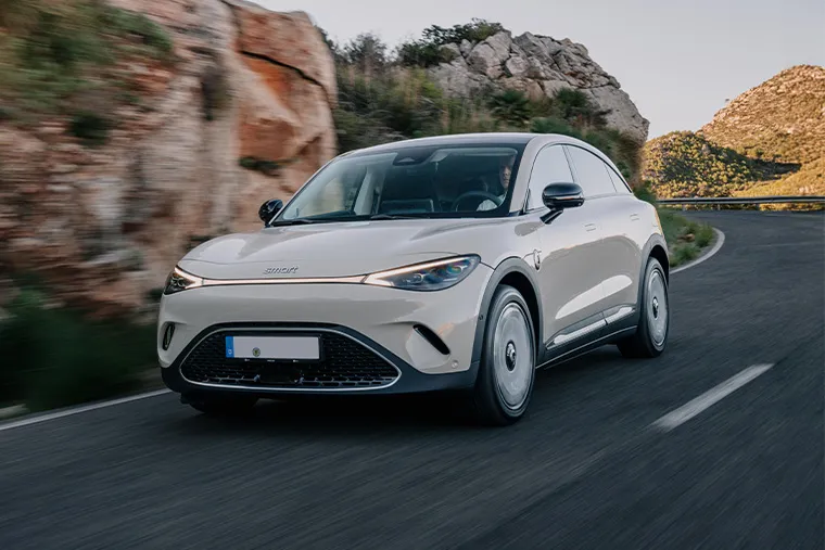 Smart #3 electric SUV in white driving on a winding mountain road, showcasing its aerodynamic front design and LED headlights