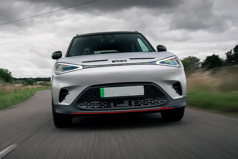 Smart #1 electric SUV driving on a country road under dark cloudy skies