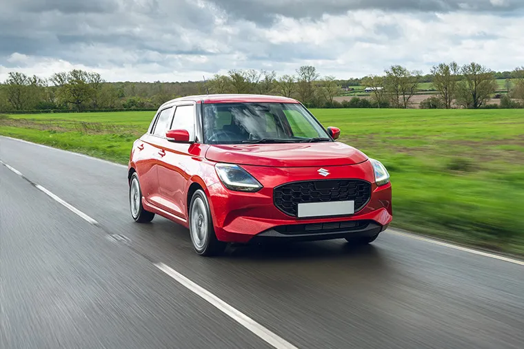 Suzuki Swift Hybrid in red driving on a country road