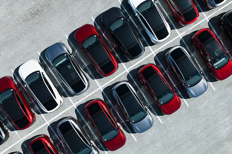 Rows of different coloured electric cars parked neatly in a lot, showcasing their sleek aerodynamic designs.
