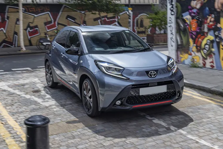 Toyota Aygo X driving through a city street with graffiti walls