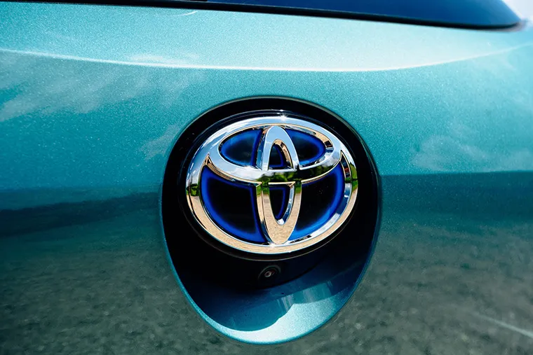 Close-up of the Toyota logo on a metallic teal car, representing the brand’s history and identity.