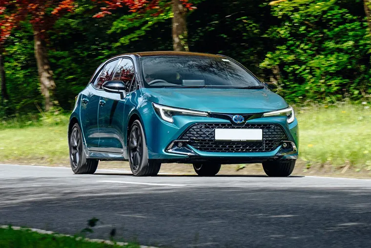 Toyota Corolla driving through a leafy countryside road, showcasing a stylish and efficient lease car option.