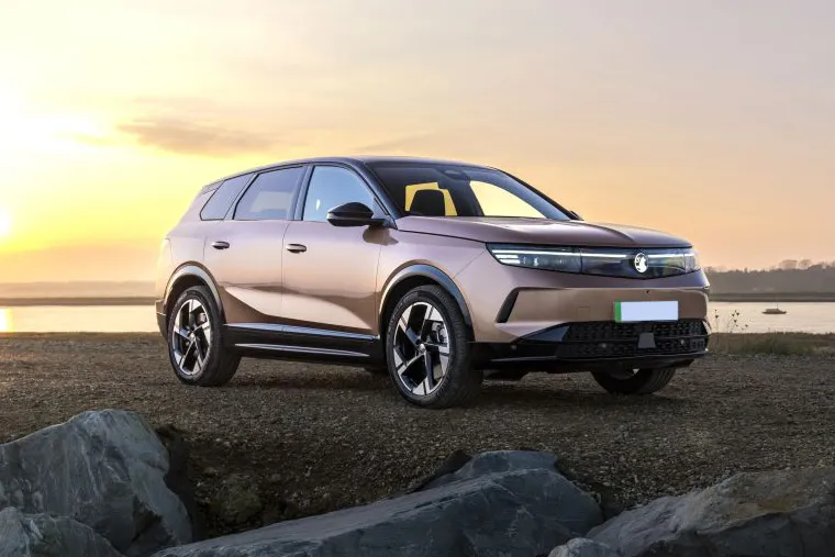 Electric Vauxhall SUV parked by a scenic lakeside at sunset.