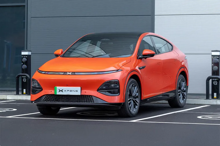 Red XPeng G6 electric SUV coupe parked in front of modern building