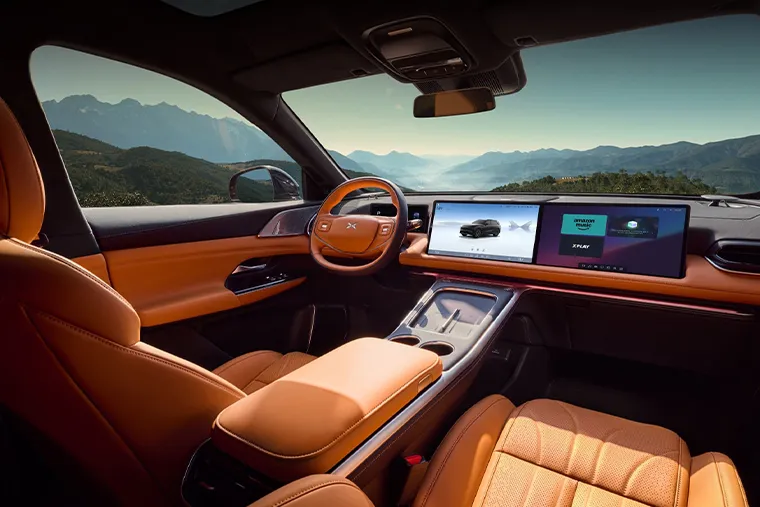 Luxury interior of 2025 XPeng G9 electric SUV with dual widescreen displays and orange leather seats