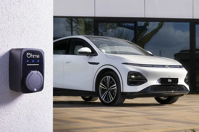 White XPeng G6 electric SUV parked outside modern building, showcasing sleek front design and LED headlights